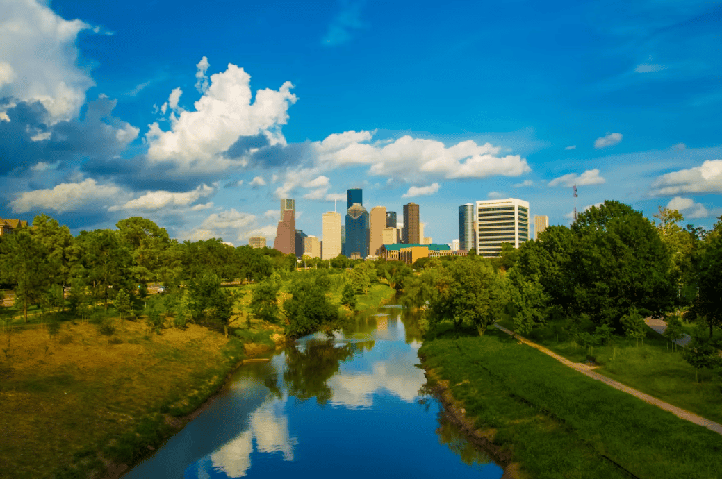 Houston, Texas skyline beyond a lush green park and peaceful river, highlighting one of the best places to retire in Texas.
