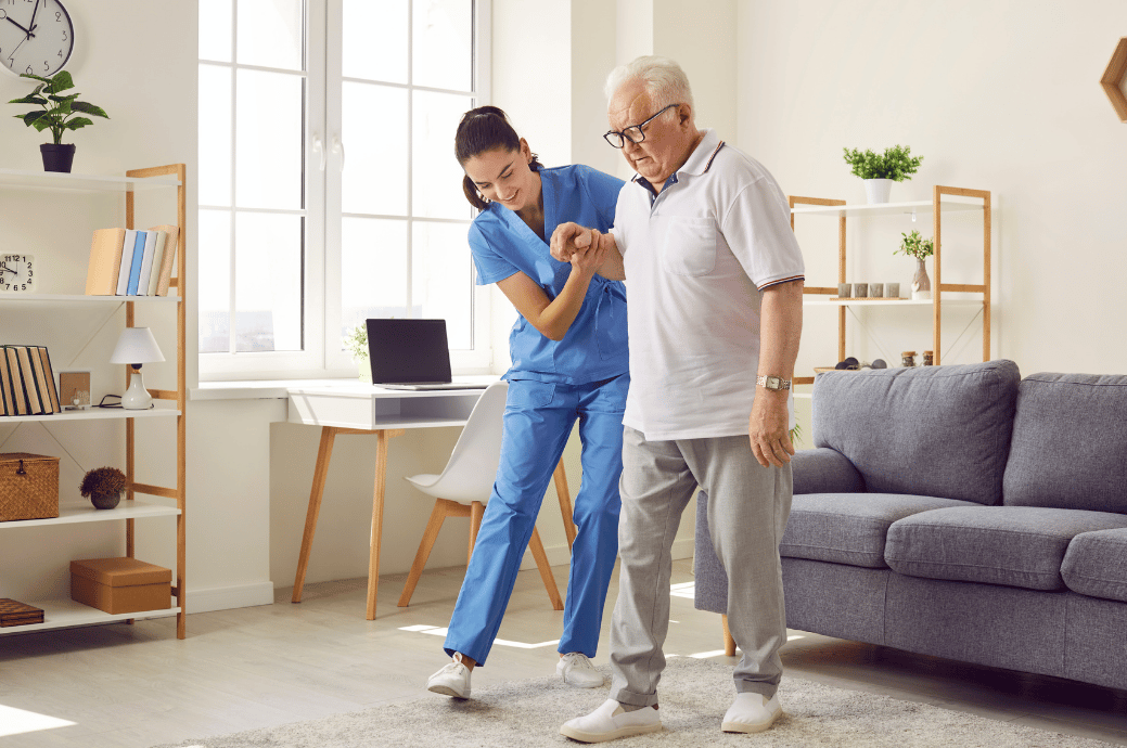 A senior living staff supporting an elderly to walk in an assisted living facility.